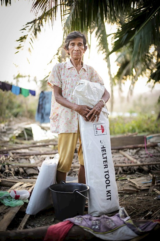 Carmelita Piguracion stands where her home used to be as she holds an emergency shelter kit provided by the Adventist Development and Relief Agency (ADRA) in the Philippines. Piguracion's home is among the 1000 homes totally destroyed by typhoon Koppu in the town of Casiguran on October 18. [ADRA Philippines]